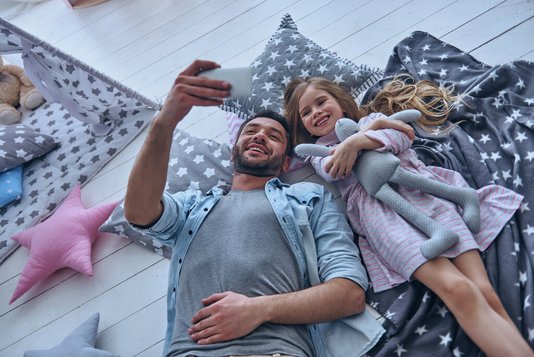 Haus-Vater-Tochter-Wohnen-Serie-4-9 Vater und Tochter liegen auf dem Boden und machen Selfies
