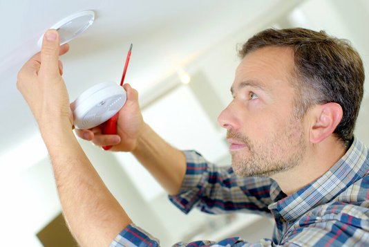 sicherheit-sicheres-haus-hilfsmittel-hilfe-achten-03 Mann bring Feuermelder an
