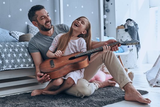 Haus-Vater-Tochter-Wohnen-Serie-4-23 Junger Vater bringt seiner Tochter das Gitarre spielen bei.